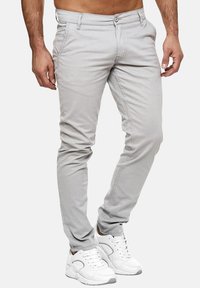 Jasnoszare chinosy o wąskim kroju, wykonane z bawełnianej mieszanki tkanin. Posiadają klasyczne kieszenie, zapięcie na guziki oraz lekko zwężane nogawki.