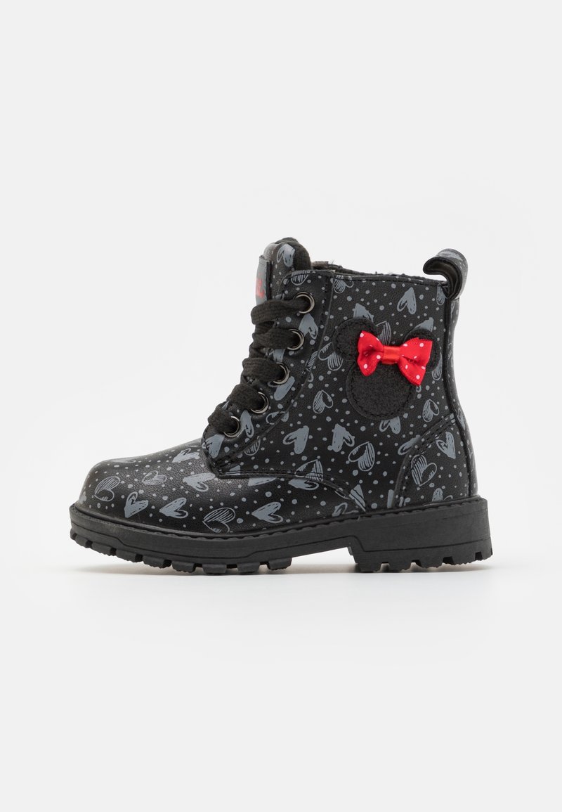 Bottines noires à lacets avec un motif en forme de cœur, accent en forme de nœud rouge, semelle en caoutchouc et finition brillante, présentant des textures contrastantes.