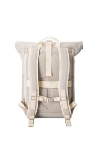 Sac à dos beige à enroulement vu de dos, avec bretelles rembourrées, dos en mesh rembourré et boucle pectorale, posé debout sur fond blanc.