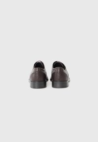 Zapatos de cuero marrón oscuro con una textura suave y perforaciones decorativas a lo largo del talón. Cuentan con una suela baja de goma negra.