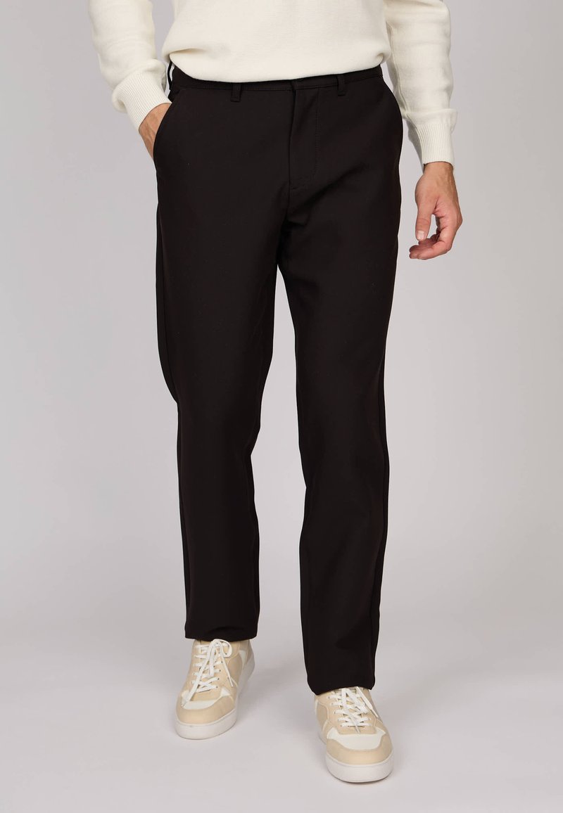 Pantalons noirs à coupe ajustée, fabriqués en tissu léger. Ils présentent une taille plate, des poches latérales et une texture propre et lisse.