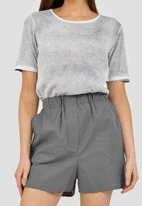Szara koszulka z prążkowanego materiału z białymi wykończeniami, zestawiona z szarymi szortami na elastycznej talii o zgrabnym kroju i z przednimi kieszeniami.