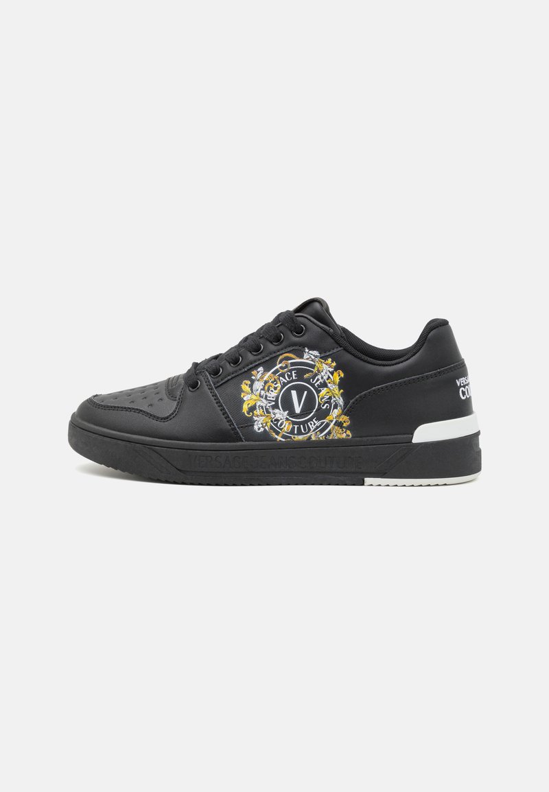 Svarte lærersneakers med perforert tå, brodert gull- og hvit detaljering, og kontrasterende hvit såle med "Versace Jeans Couture."