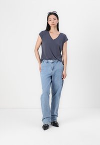 Σκούρος γκρι κοντομάνικος μπλούζα V-neck συνδυασμένη με ανοιχτό μπλε χαλαρού τύπου τζιν και μαύρες μυτερές γόβες. Απλός σχεδιασμός και απαλή υφή.