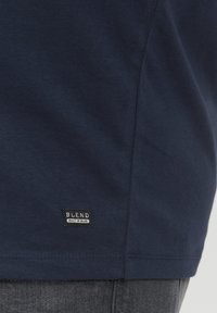 Mørkeblå bomulls T-skjorte med et lite "BLEND"-merke nær sømmen. Myk tekstur med klassisk snitt og minimal design.