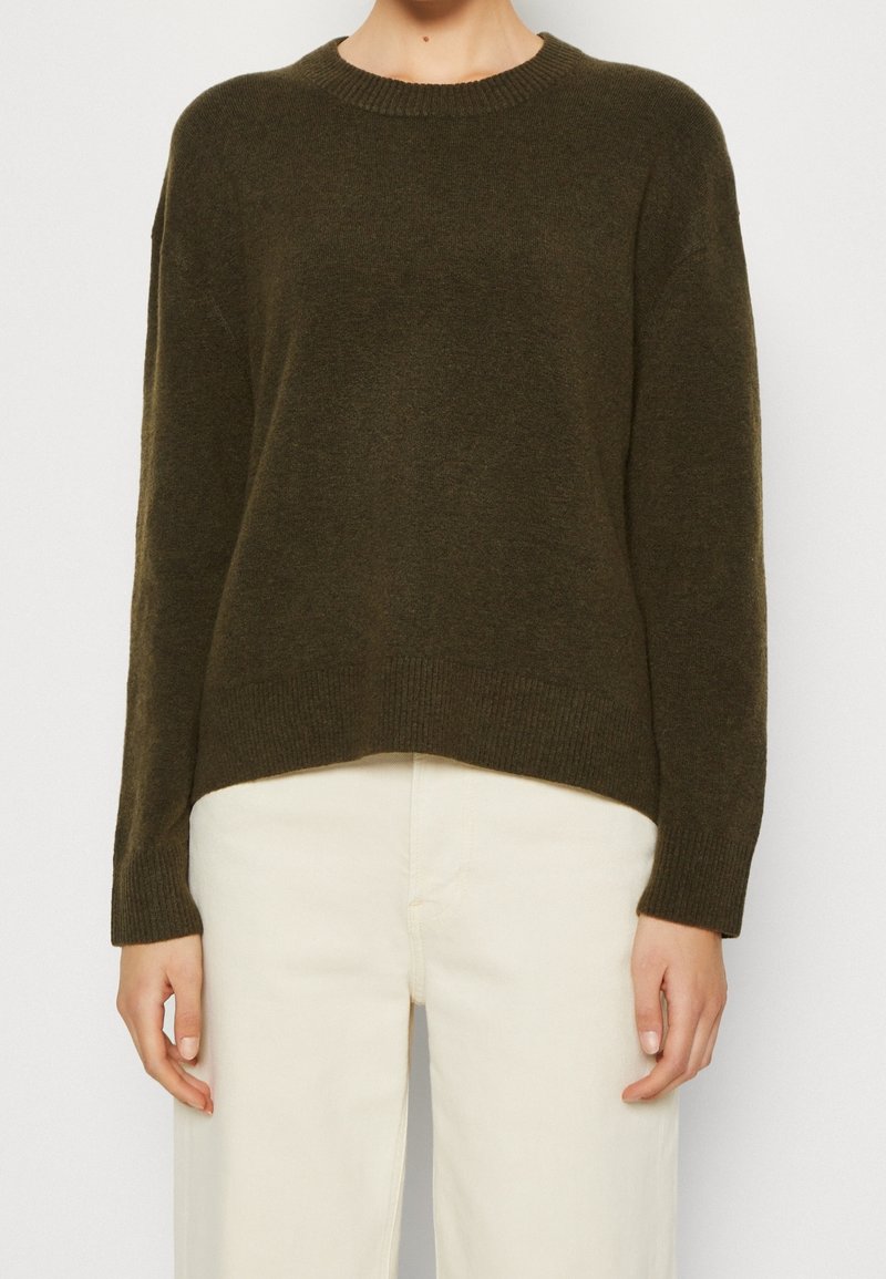 Mörkgrön tröja med rund halsringning, sänkt axelparti och ribbade ärmslut och fåll. Mjuk textur, något lös passform. Matchas med ljusa byxor.