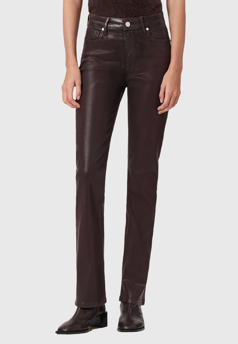 Pantaloni in pelle marrone con vestibilità slim, vita alta, tasche frontali e cuciture a contrasto. Texture liscia con finitura lucida.