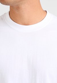 White cotton t-shirt with a crew neckline, smooth texture, and no visible patterns or logos, displaying a plain, minimalist design.