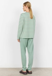 Haut à manches longues rayé vert clair avec une coupe décontractée, associé à un pantalon fuselé assorti. Le tissu semble doux avec une texture lisse.