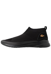 Sneaker nera slip-on con tomaia in mesh testurizzato, suola in gomma e un piccolo logo dorato sull'inserto del tallone. Design a bassa apertura con collare elastico.