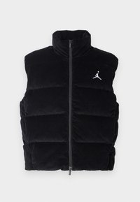 Čierny kordurový puffový vest s vysokým golierom, zipsovým zatváraním a bielym logom Jordan na hrudi, s prešívaným dizajnom.