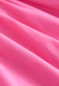 Lyserødt stof med en glat tekstur, der har bløde folder og en jævn farve, velegnet til tøj eller polstring.