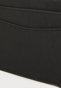 Black wallet with a textured checkered pattern, made from synthetic material. Features smooth edges and contrasting stitching detail.