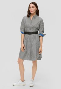 Gestreiftes Hemdblusenkleid in Schwarz und Weiß, mit einem taillierten Design, langen Ärmeln mit blauen Akzenten und einer lockeren Passform bis zur Mitte des Oberschenkels.