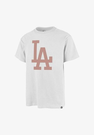 Camiseta blanca de manga corta con grandes letras "LA" en rosa apagado en la parte delantera y una pequeña etiqueta de la marca cerca del dobladillo inferior.