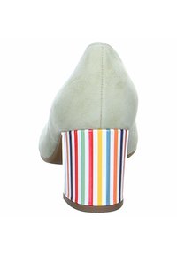 Chaussure à talon haut en suède beige avec un talon bloc rayé vertical multicolore, vue de dos sur un fond blanc.