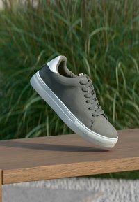 Baskets grises avec une tige lisse, des accents blancs et une semelle en caoutchouc. Dotées d'un design classique à lacets et d'un bout de chaussure texturé.