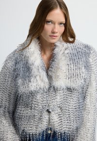 Faux-Fur-Jacke mit einem grau-weißen Muster, ausgestattet mit einem flauschigen Kragen, strukturiertem Stoff und einer Knopfleiste vorne.