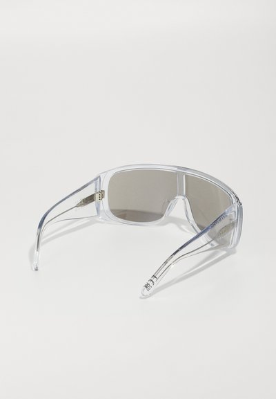 Sunglasses med klara plastbågar och bruna tonade linser. Har en rak design med böjda armar och varumärke på sidan.