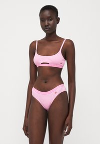 Pink ribbed bikini set featuring a cropped top with a cutout and matching high-waisted briefs, both with solid elastic bands.