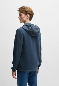 Marineblauer Kapuzenpullover aus strukturiertem Stoff mit verstellbarem Kapuzenzug. Verfügt über kontrastierende Einsätze an den Schultern und ein dezentes Logo am Ärmel.