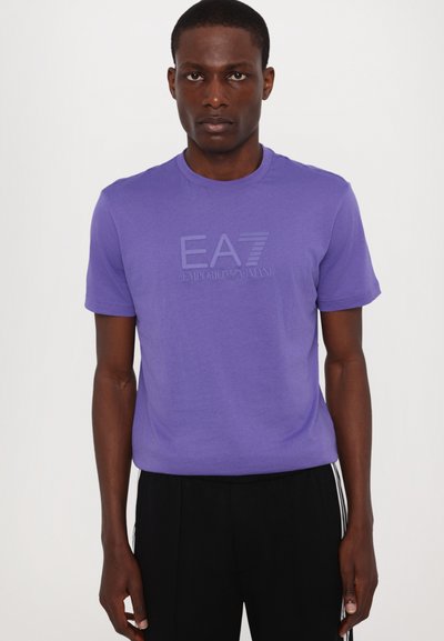 Lilla kortermet t-skjorte med en subtil preget logo "EA7 Emporio Armani" på forsiden. Mykt stoff, rund hals, normal passform.