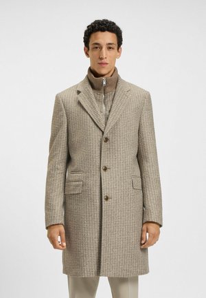 Beige houndstooth coat with a tailored fit, notch lapels, two front pockets, and brown buttons, layered over a high-collar knit sweater.