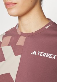 La camiseta de la marca Terrex presenta un diseño a bloques de color en mauve y beige con grandes patrones geom�étricos. Tela suave con cuello redondo.