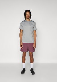 Sporty grå t-skjorte med korte ermer, lett stoff, parret med bordeauxfargede shorts. Sko: svarte joggesko, hvite sokker. Enkelt design, ingen mønstre.