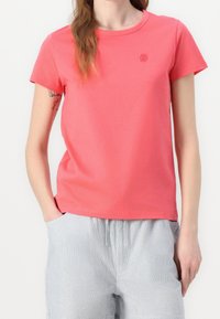 Coral short-sleeve T-shirt made of cotton, featuring a round neckline and a subtle embroidered logo on the chest. Smooth texture.
