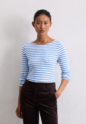 Haut à rayures bleues et blanches à manches longues avec un décolleté large, associé à un pantalon taille haute marron foncé, doté de poches latérales.