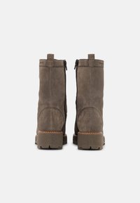 Graue Wildleder-Stiefeletten mit seitlichen Reißverschlüssen, robusten Gummisohlen und vernähten Details an Rücken und Seiten.