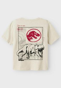 Camiseta de manga corta beige con ilustración de un dinosaurio negro y un logo circular rojo. El texto dice "Leave No Trace". Diseñada con cuello redondo.