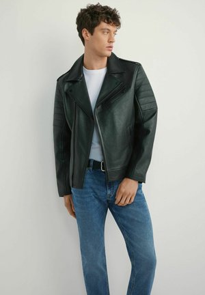 Czarna skórzana kurtka motocyklowa z pikowanymi detalami na ramionach, zestawiona z białą koszulą i niebieskimi dżinsami. Zaprojektowana z asymetrycznymi zamkami błyskawicznymi.