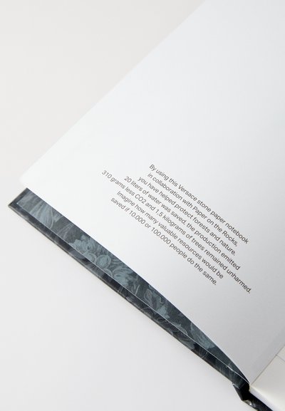 Quaderno di carta stone con copertina scura a motivo floreale. All'interno, pagine bianche e testo stampato in un font moderno sul lato destro.