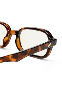 Καφέ ορθογώνιο σκελετό γυαλιών με μοτίβο χελώνας και διάφανοι φακοί, ε μφανιζόμενο σε κοντινή όψη σε λευκό φόντο.