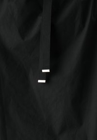 Tessuto nero con due lunghe cinghie nere dotate di clip metalliche alle estremità. Il tessuto ha una texture liscia e un leggero lucido.