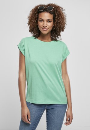 Mintgrønn kortermet t-skjorte med rullekanter, myk bomullstekstur, avslappet passform og rund hals, kombinert med blå denimjeans.