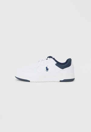 Baskets blanches avec une finition en cuir lisse, accents marine au niveau du talon et de la languette, détails perforés et une semelle en caoutchouc texturée.