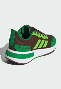 Hnedé tenisky s akcentmi v zelenej farbe a textúrovanými panelmi. Obsahujú bielu medzipodrážku, tri zelené pruhy a branding "Minecraft" na pätke.