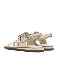 Beige leren sandalen met een platte zool, voorzien van twee brede banden met zilveren gespen en een minimalistisch ontwerp. Zachte voetbed voor comfort.