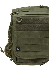 Olivgrön taktisk väska tillverkad av slitstarkt tyg, med zippered topp, meshsidoficka och Velcro-område för lappar. Inkluderar justerbara remmar.