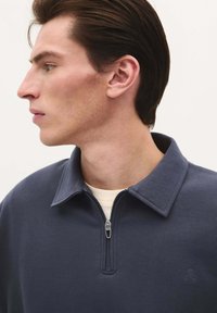Marineblauwe rits-sweater met een kraag, gemaakt van zachte stof, met een subtiele logo op de borst.