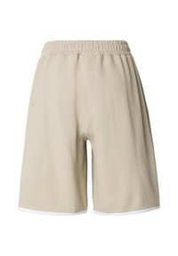 Beige waffle-textured shorts with an elastic waistband and white trim. Loose fit with a knee-length cut and no pockets visible.
