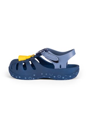 Blaue Gummisandale mit ausgeschnittenen Riemen, verstellbarem Schnallenverschluss und einer strukturierten Sohle mit kreisförmigen Mustern. Leichtes und flexibles Design.