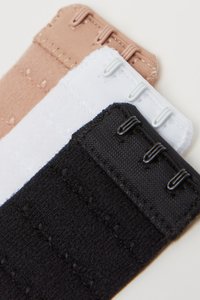 Tres tiras elásticas en beige, blanco y negro, con múltiples ganchos y una tela texturizada, diseñadas para un ajuste seguro.