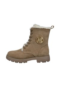 Sandfarbene Wildleder-Stiefelette mit Kunstfellfutter, auffälligem runden goldenen Logo, sechs Schnürsenkellochungen und einer robusten Gummisohle für besseren Grip.