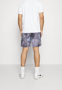 Badbyxor för herrar med ett geometriskt mönster i lila och blå nyanser, tillverkade av ett lätt och snabbtorkande material. Badbyxorna har en elastisk midja.