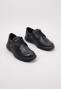 Par de zapatos casuales de cuero negro con cordones para hombre, con un acabado texturizado y suelas de goma resistentes, sobre un fondo claro.