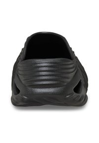 Czarne buty slip-on z teksturowanego materiału gumowego, z rowkowanymi detalami i wycięciami po bokach dla wentylacji. Okrągły tył.
